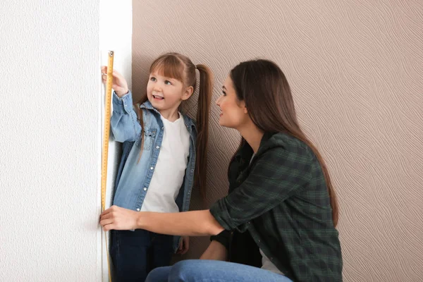 若い女性の屋内で彼女の娘の高さを測定 — ストック写真