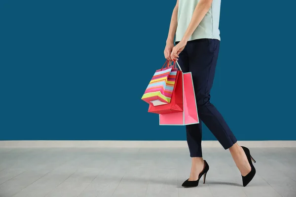 Mujer joven con bolsas de compras contra la pared de color —  Fotos de Stock