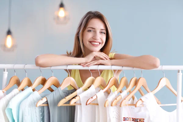 Young woman standing near clothes rack indoors. Stylish wardrobe — Stock Photo, Image