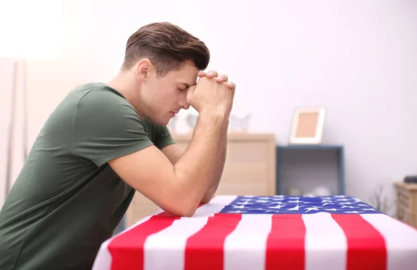 Man praying over American flag at home — Stock Photo, Image