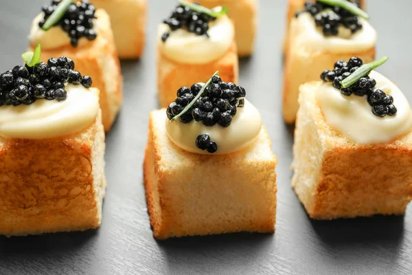 Delikata kanapéer med svart kaviar på mörk bakgrund — Stockfoto