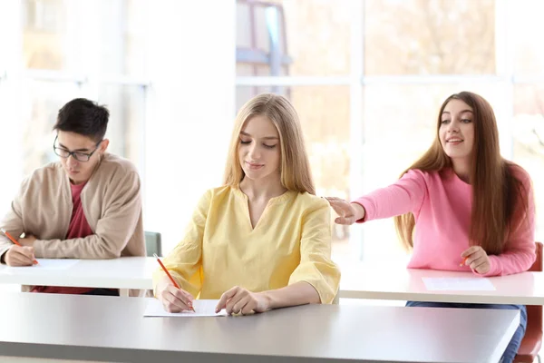 Vrouwelijke student vragen antwoorden van klasgenoot op examen — Stockfoto