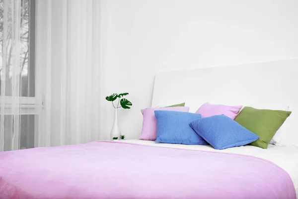 Удобная кровать с мягкими подушками в современном номере — стоковое фото