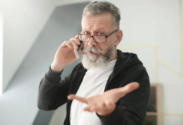Starší muž mluví na mobilním telefonu na pracovišti v úřadu — Stock fotografie