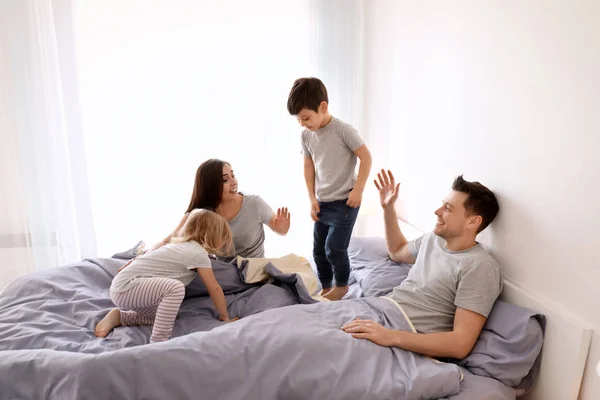 Anak-anak lucu dengan orang tua bersenang-senang di tempat tidur bersama di rumah — Stok Foto