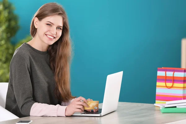 Молодая женщина делает покупки онлайн с кредитной картой и ноутбуком за столом — стоковое фото