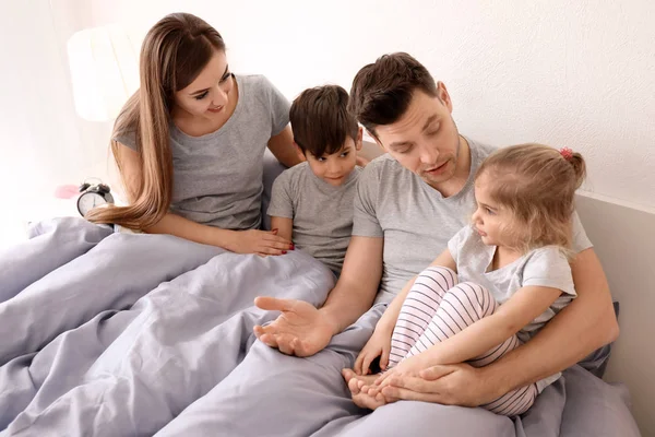 Счастливая семья с детьми на кровати дома — стоковое фото