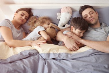 evde yatakta uyuyan aile
