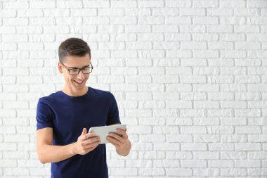 Tuğla duvar arka plan üzerinde tablet bilgisayar kullanan genç adam