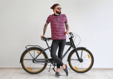 Beyaz duvar yakınındaki bisiklet ile yakışıklı hipster portresi