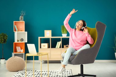 Güzel genç kadın evde rahat koltukta otururken müzik