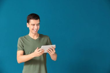 Tablet bilgisayar renk arka plan üzerinde kullanan genç adam