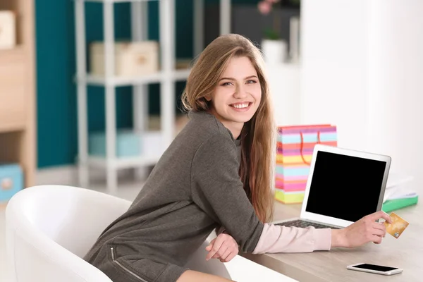 Junge Frau kauft online mit Kreditkarte und Laptop am Tisch ein — Stockfoto