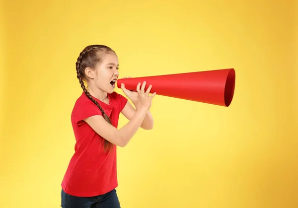 Kleines Mädchen schreit in ein Megafon aus Papier auf farbigem Hintergrund — Stockfoto