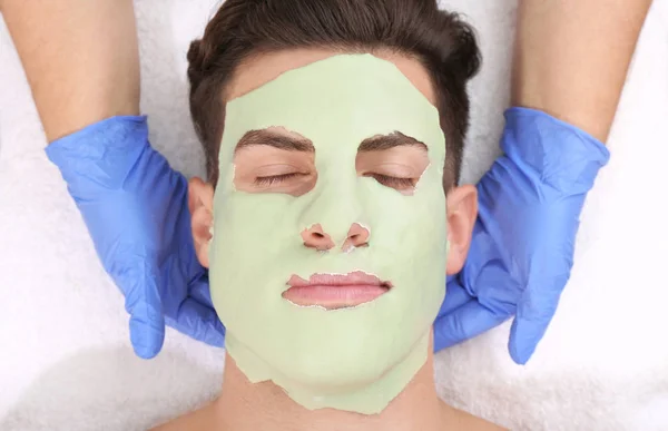 Young man with facial mask in beauty salon — Stock Photo, Image
