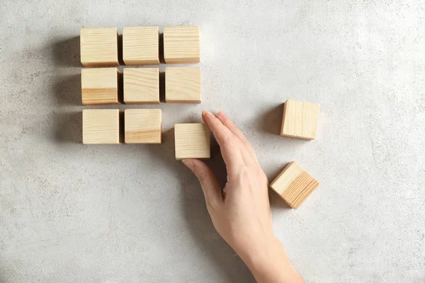 Frau mit Holzwürfeln auf hellem Hintergrund. Einheitskonzept — Stockfoto