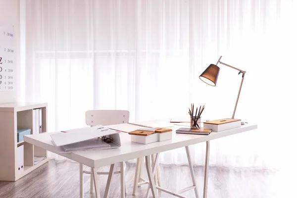 舒适的工作场所与现代台灯在桌上 — 图库照片
