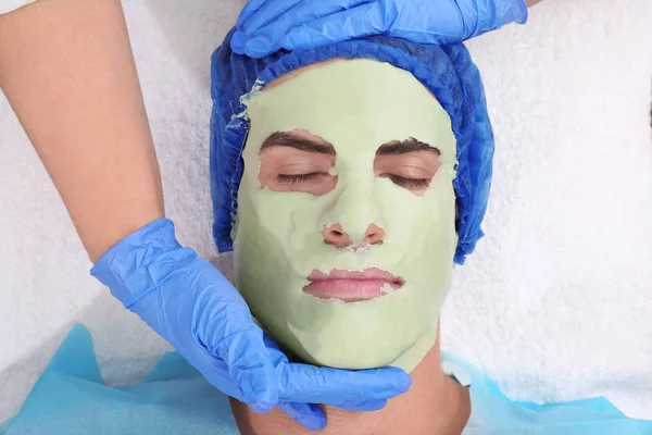 Young man with facial mask in beauty salon