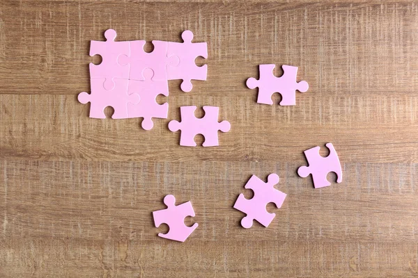 Puzzle de piezas sobre fondo de madera. Concepto de unidad —  Fotos de Stock