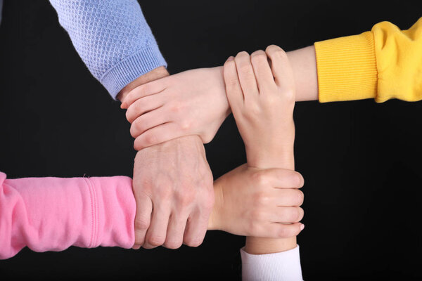 People holding hands together on black background. Unity concept
