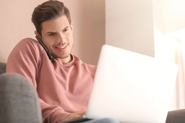 Jeune homme parlant sur un téléphone portable tout en travaillant au bureau à domicile — Photo