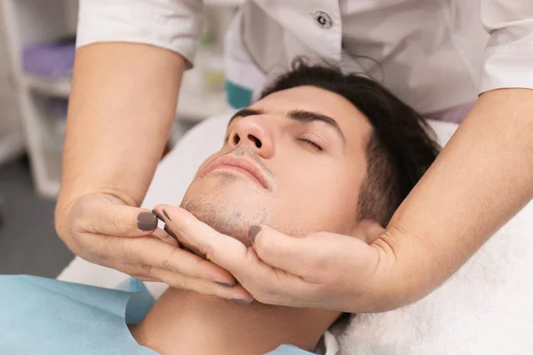 Joven hombre teniendo masaje facial en salón de belleza —  Fotos de Stock