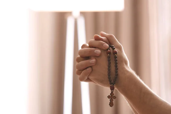 Mains de jeunes religieux avec des perles de chapelet priant à la maison — Photo