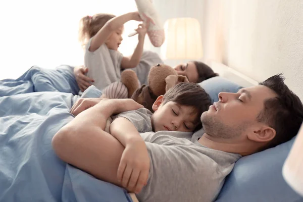 Симпатична пробуджена дівчина грає біля сплячої сім'ї на ліжку вдома — стокове фото