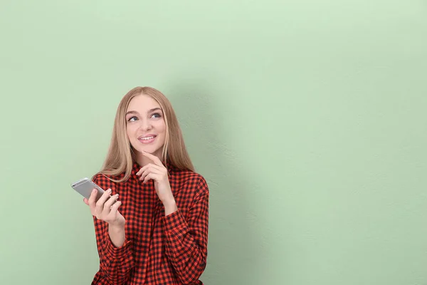 Mooie jonge vrouw met mobiele telefoon in de buurt van kleur muur — Stockfoto