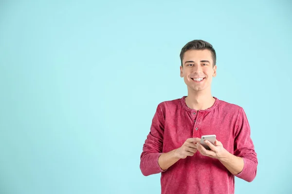 Hombre joven usando el teléfono en el fondo de color —  Fotos de Stock