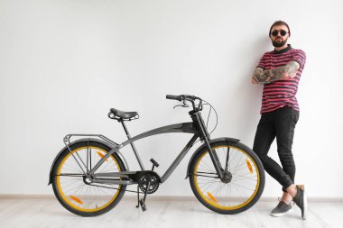 Beyaz duvar yakınındaki bisiklet ile yakışıklı hipster portresi
