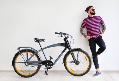 Beyaz duvar yakınındaki bisiklet ile yakışıklı hipster portresi