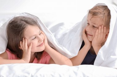 Mutlu küçük kardeşim ve kız kardeşi yatak battaniyenin altında yatan portresi