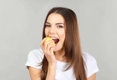 Güzel genç kadın olgun limon gri arka plan üzerinde yemek