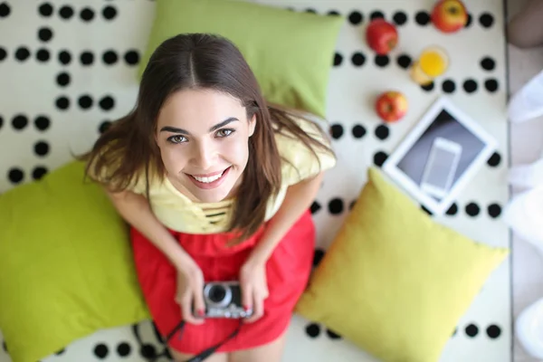 Beautiful young woman with camera on carpet, top view — Stock Photo, Image