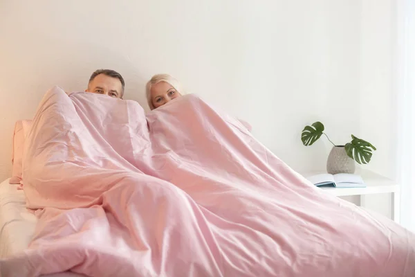 Pareja mayor escondida bajo una manta en la cama juntos —  Fotos de Stock