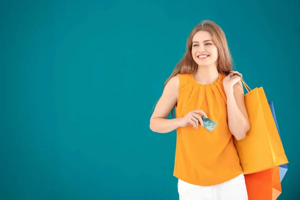Schöne Junge Frau Mit Einkaufstaschen Und Kreditkarte Auf Farbigem Hintergrund — Stockfoto