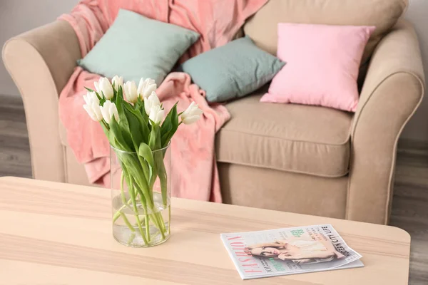 Деревянный стол с букетом тюльпанов возле дивана в гостиной — стоковое фото