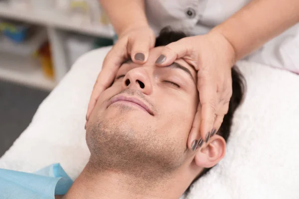 Joven hombre teniendo masaje facial en salón de belleza — Foto de Stock