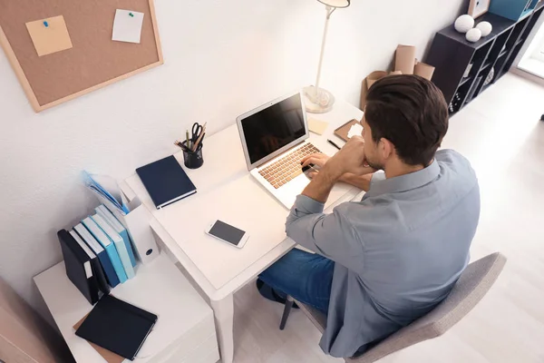 Hombre joven que trabaja con el ordenador portátil en la mesa en la oficina — Foto de Stock