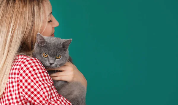 Junge Frau mit niedlichem Haustier Katze auf farbigem Hintergrund — Stockfoto