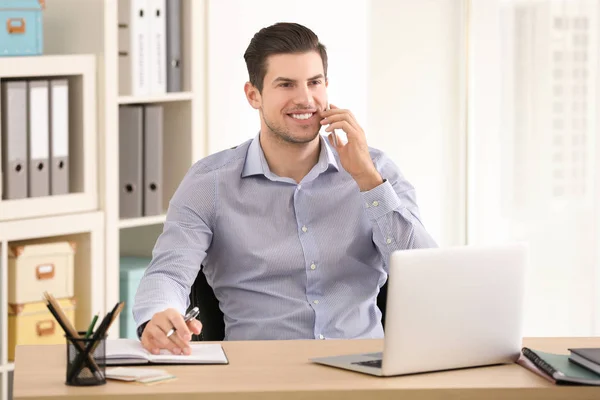 Ung man pratar i mobiltelefon medan arbetande i kontor — Stockfoto