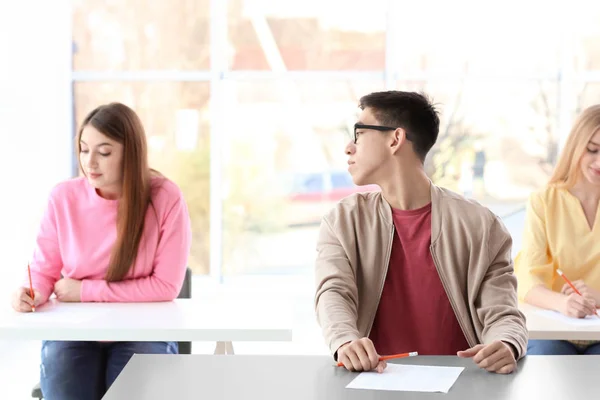 Estudante asiático tentando copiar respostas de colega de classe no exame — Fotografia de Stock