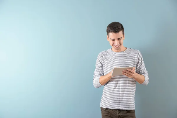 Hombre joven usando tableta en fondo de color — Foto de Stock