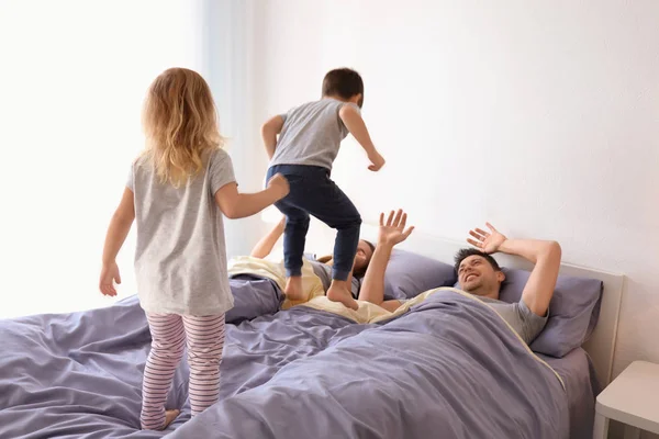 Crianças bonitas com pais se divertindo na cama juntos em casa — Fotografia de Stock