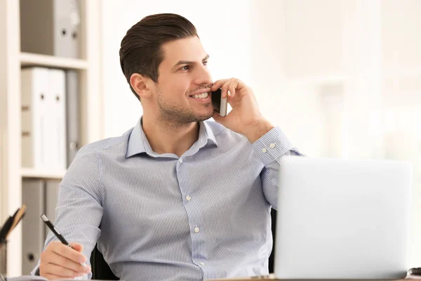 Young man talking on mobile phone while working in office — Stock Photo, Image