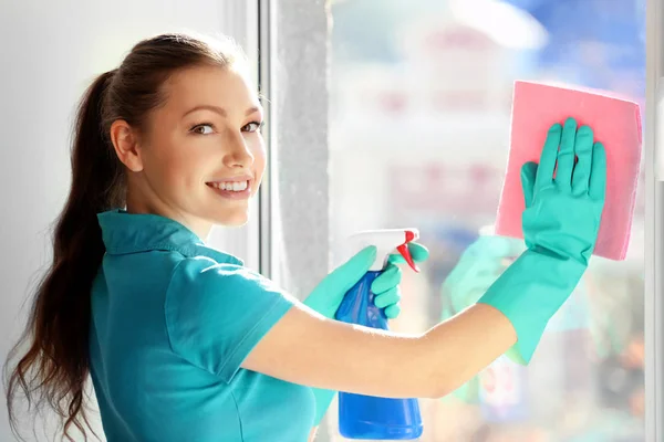 Young woman cleaning window indoors — Stock Photo, Image