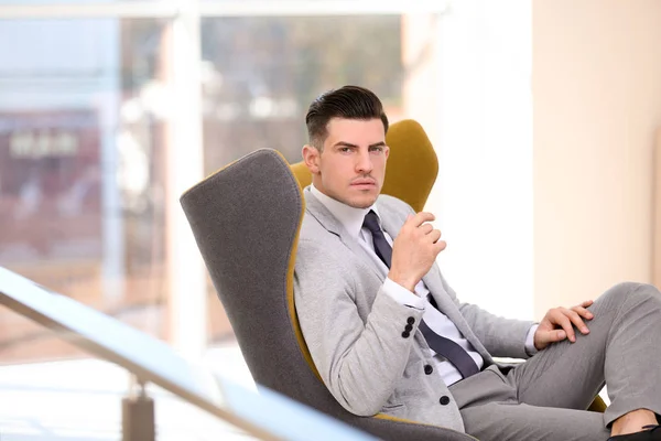 Hombre de negocios guapo sentado en cómodo sillón en el interior —  Fotos de Stock
