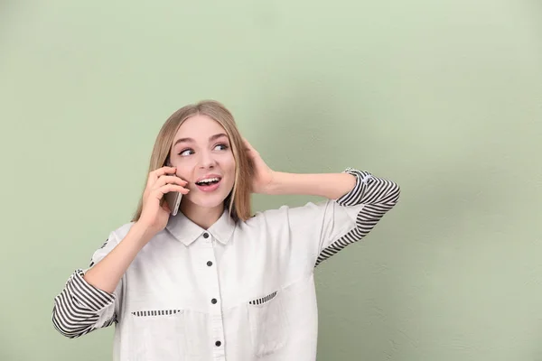 Vacker ung kvinna som pratar i mobiltelefon nära färg vägg — Stockfoto