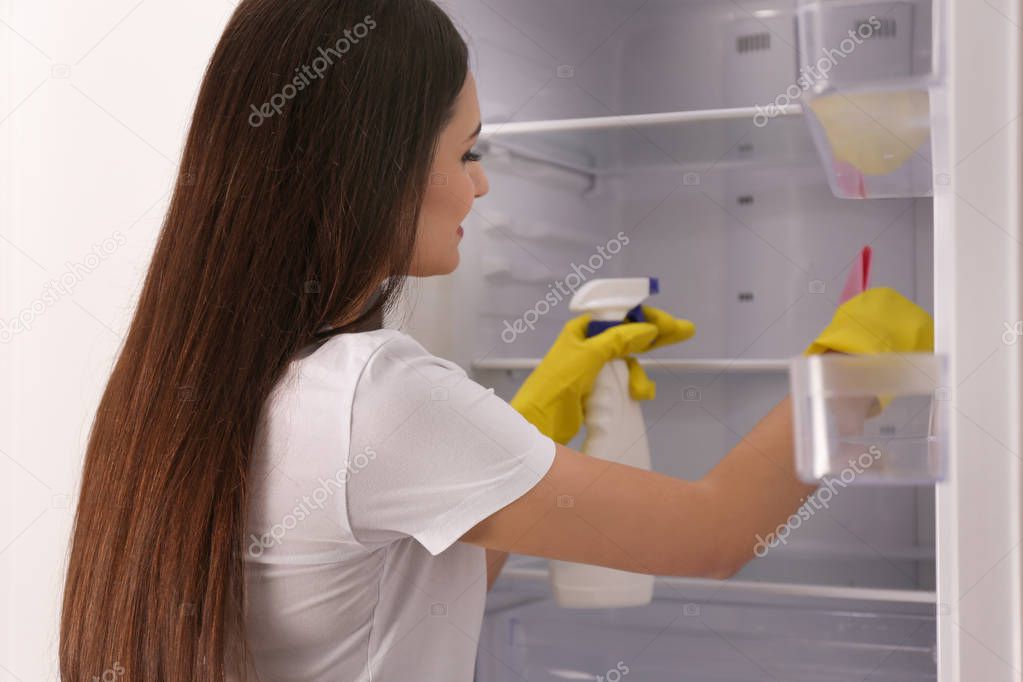 Woman cleaning empty refrigerator at home